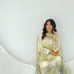 South Asian woman in traditional dress poses elegantly against a white background.