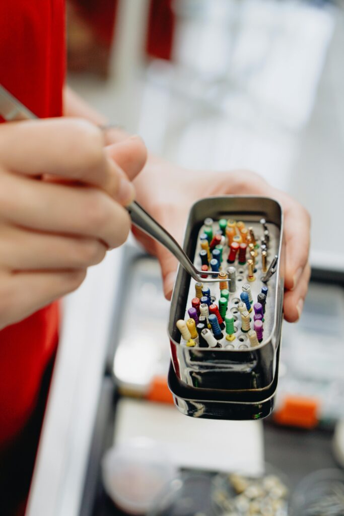 pexels photo 13207299 13207299 Detailed close-up of dental instruments in a sterilization box held by hand with forceps.